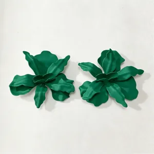 Detailopname van groene metalen bloemoorringen met een ingewikkeld gelaagd bloembladontwerp.