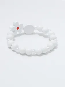 Close-up van de witte kralenarmband met een schattige bloemhangertje en gladde kralen.