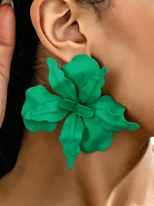 Gedetailleerde close-up van opvallende grote groene bloemmetalen oorbellen gedragen.