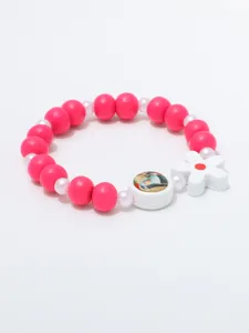 Detail van de roze houten kralenarmband met witte bloemhangertje en een ronde portretkraal.