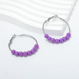 Detailed shot of trendy purple beaded hoop earrings, stylish retro metal design for women.