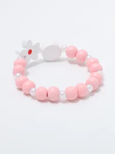 Detailopname van schattige roze kralenarmband met witte bloemhangel, prachtig kindersieraad.