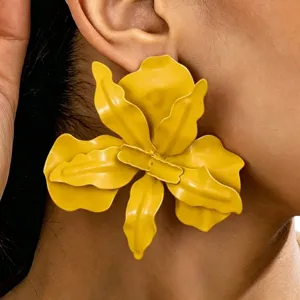 Hoofdafbeelding van overdreven grote gele metalen bloem oorbellen gedragen, opvallende sieraden.