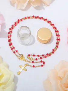 Collana rosario con perle rosse e ciondolo croce dorata in confezione di bottiglia, gioiello religioso.