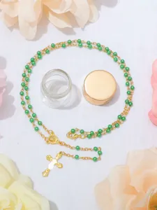 Vista dettagliata della collana del rosario di perle verdi con croce in lega dorata.