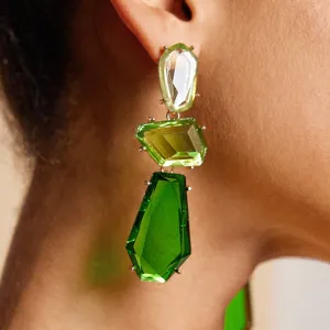Detailopname van opvallende geometrische groene oorbellen met meerlaagse stenen.