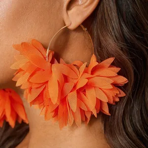 Detail van feloranje chiffon bloemblad creolen in close-up, modieuze oorbellen voor dames.