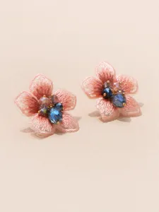 Close-up detail van prachtige roze stoffen bloem oorknopjes met glinsterende kristal kralen.