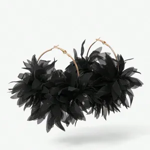 Detail van zwarte chiffon bloem creolen oorbellen met gouden metalen ringen.