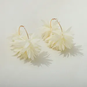 Detailopname van witte chiffon bloemblad oorbellen met gouden ring, elegant en chique.