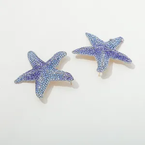 Close-up detail view of gradient blue crystal pavé starfish stud earrings in metallic finish.