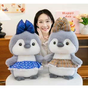 Detalle de muñeco pingüino de peluche con faldas elegantes azul y a cuadros para decoración.