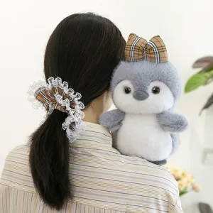Bonito muñeco de peluche de pingüino con lazo de cuadros y coletero de encaje como regalo.