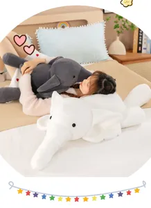 Detailed scene of a person resting with soft gray and white elephant plush pillows on bed.