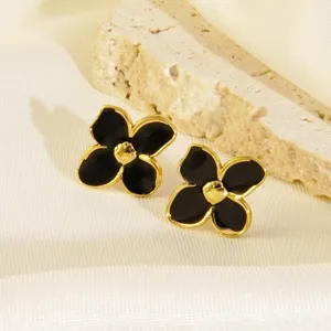 Orecchini a lobo con fiore a quattro foglie in smalto nero, elegante design in acciaio.
