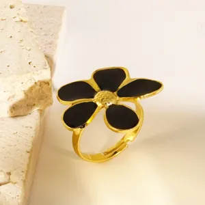 Gedetailleerde close-up van een chique vergulde bloemring met elegante zwarte emaille bloemblaadjes