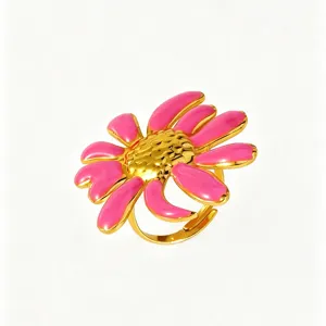 Dettaglio ravvicinato dell'anello con fiore in smalto rosa dolce, finitura in metallo dorato.