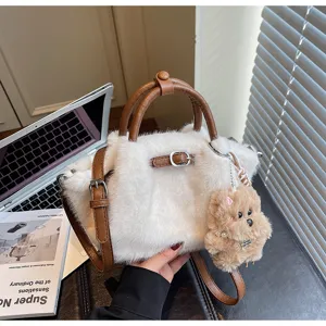 Détail de sac bandoulière en peluche, fausse fourrure blanche et poignées en cuir.