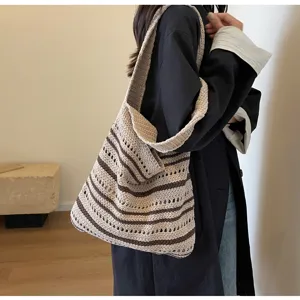 Vista detallada del bolso de hombro de punto a rayas con textura calada y estilo informal.