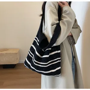 Vista detallada de un bolso de hombro tejido a rayas con un elegante diseño calado casual.