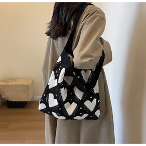 Detailed shot of a black and white heart knit shoulder bag, showcasing stylish commuter design.