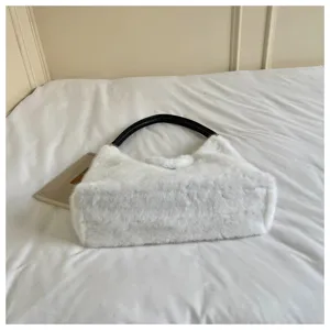 Detailed view of the stylish white fluffy plush shoulder bag with black leather handle.