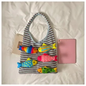Vista dettagliata di una graziosa borsa a tracolla all'uncinetto con pesci di peluche colorati.