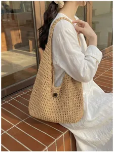 Vista dettagliata della borsa a spalla intrecciata estiva con design in paglia traforata.