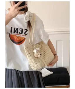 Gros plan détaillé du sac porté épaule en crochet crème avec charm ours en peluche et nœud.