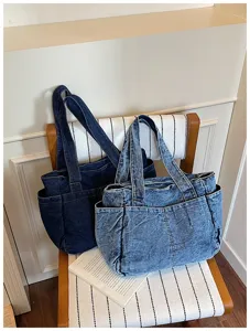 Λεπτομερής λήψη από casual τσάντες tote από πλυμένο denim με πολλές τσέπες σε καρέκλα.