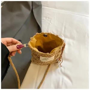 Vue détaillée d'un sac bandoulière en paille tressée bohème avec doublure jaune et pompon.