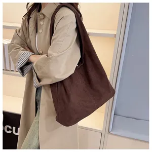 Detailed shot of brown suede shoulder tote bag worn by model in trench coat style.
