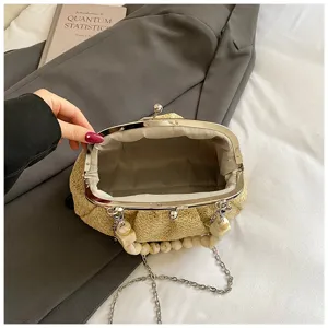 Gros plan sur le sac besace en paille tressée avec poignée perlée effet marbre.