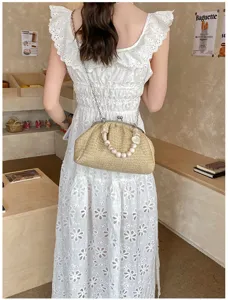 Sac de plage en paille tissée pour femme avec poignée de perles et bandoulière chaîne élégante.