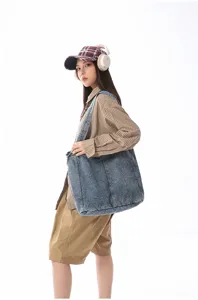 Detailed shot of a large washed denim tote bag worn by a model, showing daily casual style.