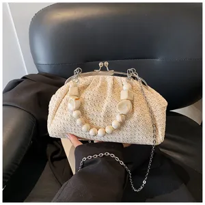 Detail de sac coquillage en paille avec poignee perlee et chaine metallique de plage.