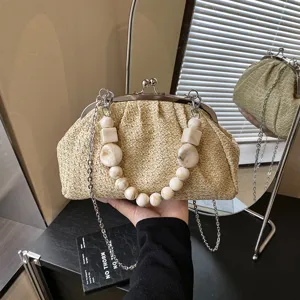 Détail du sac de paille avec poignée en perles de résine, fermoir métal et chaîne.