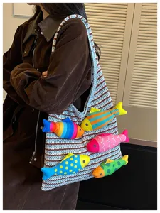 Vista dettagliata di una borsa in maglia con pesci di peluche colorati, stile casual.