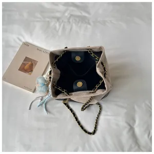 Women quilted chain bucket bag interior detail, stylish autumn winter commuter shoulder handbag.