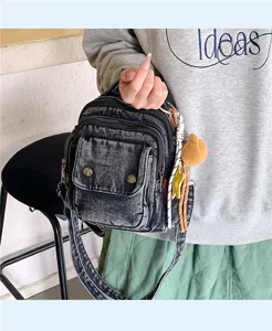 Close-up view of a vintage washed denim crossbody bag featuring multi-pockets and cute charms.