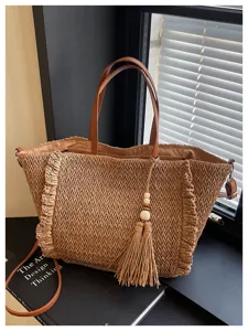 Woven straw tote bag for women with leather handles and tassel pendant. Casual beach bag.