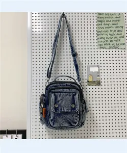 Denim crossbody bag detail, vintage washed blue fabric, multiple pockets and adjustable strap.