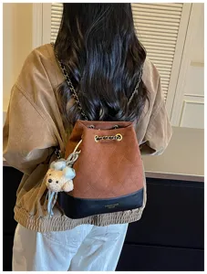 Stylish quilted bucket backpack detail showcasing brown suede and black leather with chain straps.