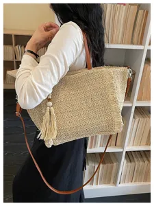 Woven straw shoulder bag for women, large capacity beach tote with stylish tassel and straps.