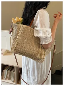 Detail shot of resort style straw shoulder bag with stylish tassels and practical design.