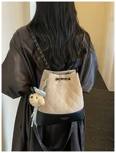Detailed view of women fashion quilted bucket backpack with chain strap and cute bear charm.