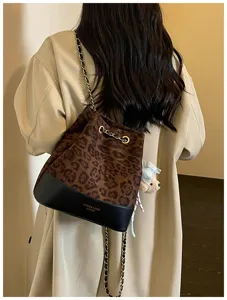 Detailed view of women's leopard print quilted bucket bag with chain strap and cute bear charm.