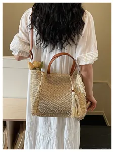 Detailed view of straw woven bag with leather handles and tassel pendant in casual vacation style.