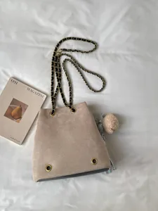 Chic beige suede bucket bag for women, featuring stylish chain shoulder strap and casual design.