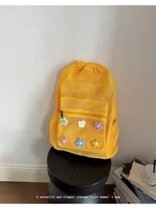 Detailed view of yellow mesh drawstring backpack featuring cute handmade crochet flower decorations.